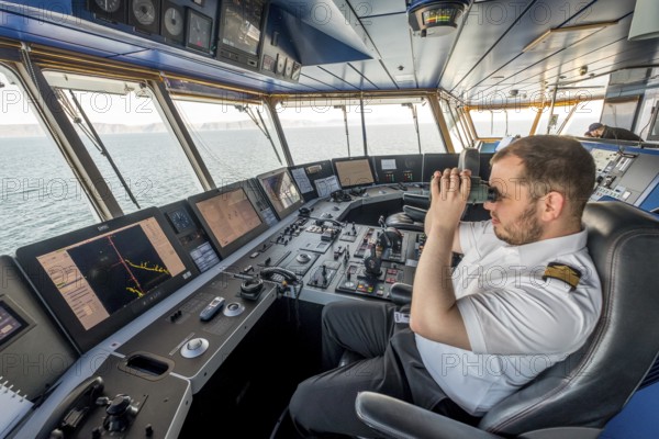 MS Polarlys, command bridge, officer on bridge, Honningsvåg, Finnmark, Norway, Scandinavia, Europe, adventure travel, binoculars, tourism, Honningsvåg, Hurtigruten, Hurtigruten voyage, command post, cruise, cruise ship, NOR, navigation technology, travel, destination, ship, shipping, ship's bridge, ship's officer, sea voyage, sighting, sightseeing, controls, tourism, Norwegian, Scandinavian, touristic