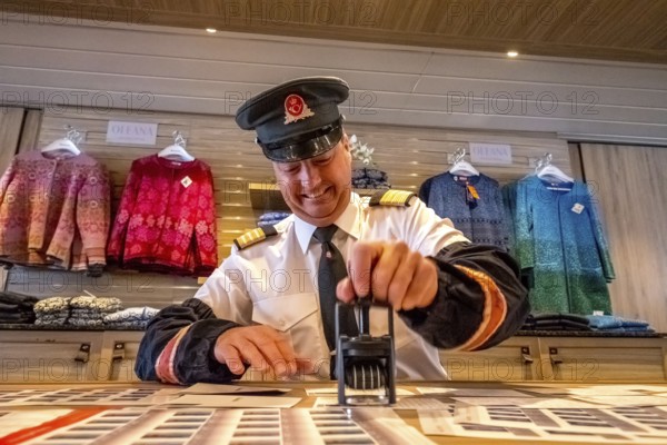Crew member stamps the mail on the mailboat, postman, ship officer, postal employee, postcard stamping, Storvik, Nordland, Norway, Scandinavia, Europe, adventure travel, tourism, Hurtigruten, Hurtigruten voyage, cruise, NOR, travel, destination, sea voyage, sightseeing, tourism, Norwegian, Scandinavian, touristic
