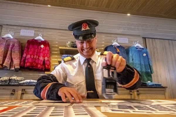 Crew member stamps the mail on the mailboat, postman, ship officer, postal employee, postcard stamping, Storvik, Nordland, Norway, Scandinavia, Europe, adventure travel, tourism, Hurtigruten, Hurtigruten voyage, cruise, NOR, travel, destination, sea voyage, sightseeing, tourism, Norwegian, Scandinavian, touristic