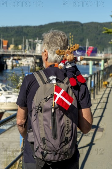 Tourist with backpack and cloth cup and Norwegian flag, travel guide, tour guide, tourist guid, Trondheim, Trøndelag, Norway, Scandinavia, Europe, adventure travel, tourism, Hurtigruten, Hurtigrutenreise, cruise, NOR, travel, destination, sea voyage, sightseeing, tourism, Trøndelag, Norwegian, Scandinavian, touristic