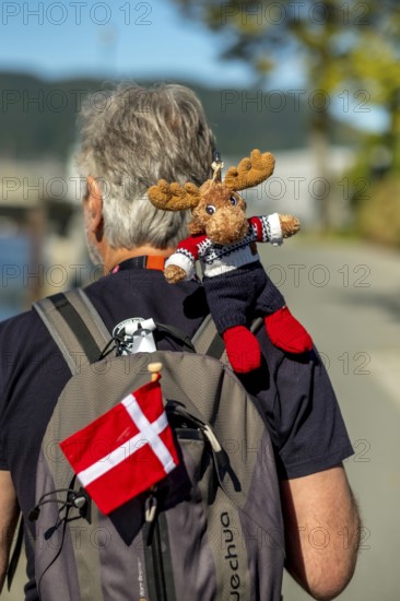 Tourist with backpack and cloth cup and Norwegian flag, travel guide, tour guide, tourist guid, Trondheim, Trøndelag, Norway, Scandinavia, Europe, adventure travel, tourism, Hurtigruten, Hurtigrutenreise, cruise, NOR, travel, destination, sea voyage, sightseeing, tourism, Trøndelag, Norwegian, Scandinavian, touristic