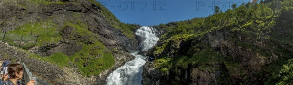 Kjosfossen waterfall, tourist looking at waterfall near Fureberget, rock faces, trees, sky, Flåm, Sogn og Fjordane, Norway, Scandinavia, Europe, Flåm, NOR, travel, tourism, destination, sightseeing, sea voyage, Hurtigruten, Hurtigruten trip, tourism, Norwegian, Scandinavian, tourist, cruise, adventure trip, waterfall, mountains, Flam Railway, Flam Railway, Flam Railway, railway trip, tour, travel by Flam Railway, Flam Railway