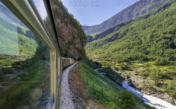Journey by Flam Railway, iron railway journey, view from Flåmsbana, Ryavegen, entrance to tunnel, mountains, forests, meadows, fjord, blue sky, Flåm, Sogn og Fjordane, Norway, Scandinavia, Europe, Flåm, NOR, travel, tourism, destination, sightseeing, sea voyage, Hurtigruten, Hurtigruten trip, tourism, Norwegian, Scandinavian, tourist, cruise, adventure trip, trees, tree, forest, forestry, forestry, hill, gravel, wooden house, valley, road, tunnel, power lines