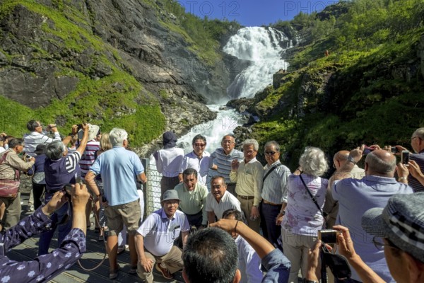 Kjosfossen waterfall, photographing tourists, waterfall near Fureberget, mountain, rock faces, meadow, trees, sky, Flåm, Sogn og Fjordane, Norway, Scandinavia, Europe, Flåm, NOR, travel, tourism, destination, sightseeing, sea voyage, Hurtigruten, Hurtigruten trip, tourism, Norwegian, Scandinavian, touristic, cruise, adventure trip, waterfall, waters, mountains, Flamsban, Flamsbana, railway journey, tour, travel by Flam railway, Flam railway