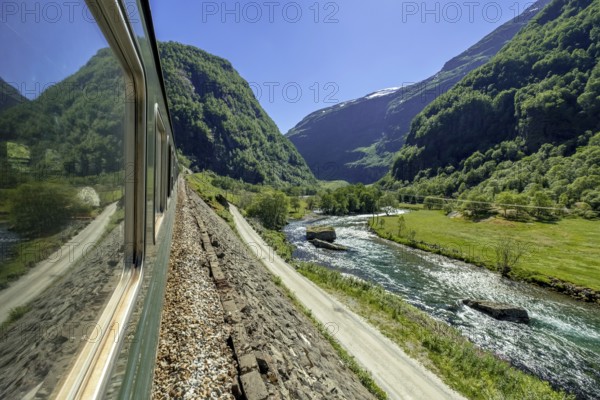 Travelling by Flam Railway, iron railway journey, view from Flåmsbana, Ryavegen, mountains, forests, meadows, blue sky, Flåm, Sogn og Fjordane, Norway, Scandinavia, Europe, Flåm, NOR, travel, tourism, destination, sightseeing, sea voyage, Hurtigruten, Hurtigruten trip, tourism, Norwegian, Scandinavian, tourist, cruise, adventure trip, trees, tree, forest, forestry, forestry, hill, gravel, snow peak, valley, road, power lines