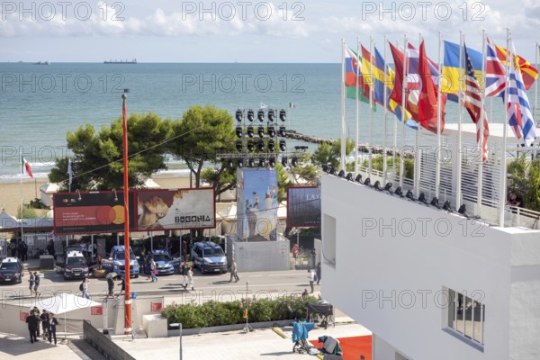 Venice, Italy - 2 September 2025: Spectators and guests walk past a film poster in front of the Palazzo del Cinema during the 82nd Venice International Film Festival