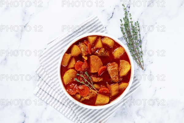 Meat goulash with potatoes and carrots, sweet peppers, in a saucepan, top view, traditional Hungarian soup, homemade, no people