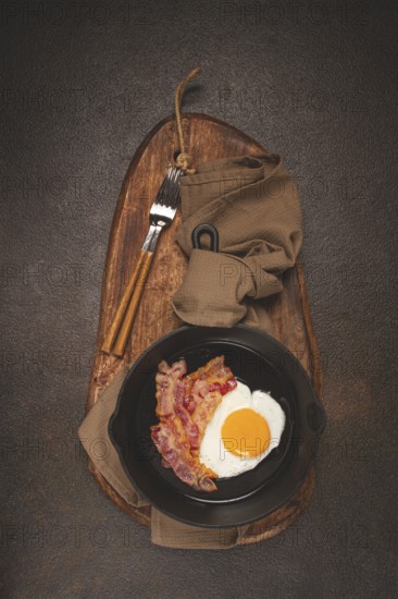 Fried egg with bacon, in a cast-iron pan, breakfast, top view, close-up, homemade, no people