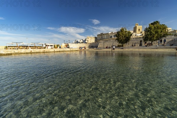 City beach Spiaggetta del Molo or Spiaggia dei Bambini and the old town centre of Otranto, Apulia, Italy