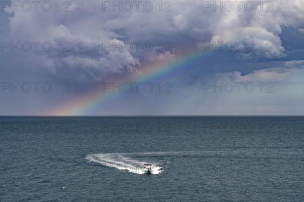 Rainbow over the Adriatic Sea and motorboat near Polignano a Mare, Apulia, Italy
