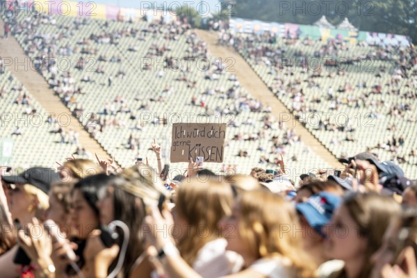 Festival visitors hold up a sign I'd like to kiss you at 01099 at the Superbloom Festival, day 2 in the Olympic Park, Munich, 31-08-2025