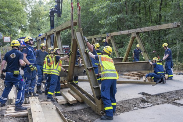 Construction of a temporary bridge over a slipped road crossing a stream, by the bridge construction section of the THW, 18 metre long steel bridge of the Krupp-D type, is assembled in around 8 hours, large-scale exercise FÜLEX25 lasting several days, of the THW North Rhine-Westphalia regional association, over 3500 volunteers from the 127 North Rhine-Westphalia local associations practise on 4 weekends, many different deployment scenarios