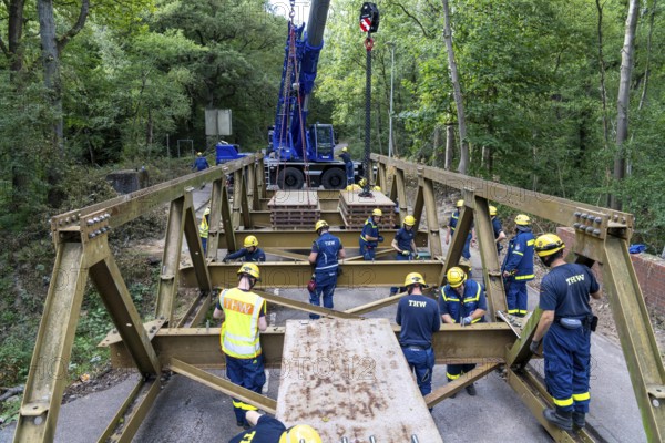 Construction of a temporary bridge over a slipped road crossing a stream, by the bridge construction section of the THW, 18 metre long steel bridge of the Krupp-D type, is assembled in around 8 hours, large-scale exercise FÜLEX25 lasting several days, of the THW North Rhine-Westphalia regional association, over 3500 volunteers from the 127 North Rhine-Westphalia local associations practise on 4 weekends, many different deployment scenarios