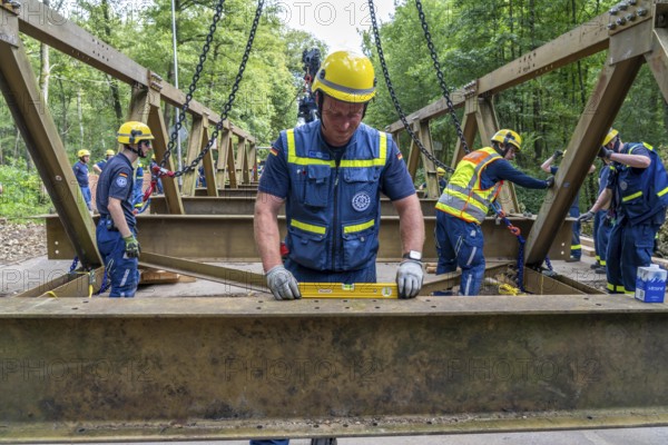 Construction of a temporary bridge over a slipped road crossing a stream, by the bridge construction section of the THW, 18 metre long steel bridge of the Krupp-D type, is assembled in around 8 hours, large-scale exercise FÜLEX25 lasting several days, of the THW North Rhine-Westphalia regional association, over 3500 volunteers from the 127 North Rhine-Westphalia local associations practise on 4 weekends, many different deployment scenarios