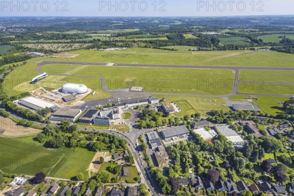 Aerial view, Essen/Mülheim Airport, Goodyear airship Zeppelin, construction site next to the WDL airship hangar, construction site and new office buildings with multi-storey car park (Pitstop centre), parked aircraft, runway and landing strip, Holthausen - Southeast, Mülheim an der Ruhr, Ruhr area, North Rhine-Westphalia, Germany, construction work, construction area, building site, building plots, construction project, construction site, DE, Europe, aerial view, aerial photography, aerial photography, overview, bird's-eye view, overview