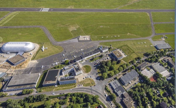 Aerial view, Essen/Mülheim Airport, construction site next to the WDL airship hangar, construction site and new office buildings with multi-storey car park (Pitstop centre), parked aircraft, runway and landing strip, Holthausen - south-east, Mülheim an der Ruhr, Ruhr area, North Rhine-Westphalia, Germany, construction work, construction area, building site, building plots, construction project, construction site, DE, Europe, aerial view, aerial photography, aerial photography, overview, bird's-eye view, overview