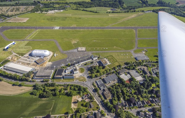 Aerial view, Essen/Mülheim Airport, Goodyear airship Zeppelin, construction site next to the WDL airship hangar, construction site and new office buildings with multi-storey car park (Pitstop centre), parked aircraft, runway and landing strip, Holthausen - Southeast, Mülheim an der Ruhr, Ruhr area, North Rhine-Westphalia, Germany, construction work, construction area, building site, building plots, construction project, construction site, DE, Europe, aerial view, aerial photography, aerial photography, overview, bird's-eye view, overview