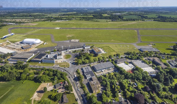 Aerial view, Essen/Mülheim Airport, Goodyear airship Zeppelin, construction site next to the WDL airship hangar, construction site and new office buildings with multi-storey car park (Pitstop centre), parked aircraft, runway and landing strip, Holthausen - Southeast, Mülheim an der Ruhr, Ruhr area, North Rhine-Westphalia, Germany, construction work, construction area, building site, building plots, construction project, construction site, DE, Europe, aerial view, aerial photography, aerial photography, overview, bird's-eye view, overview