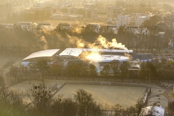 Aerial view, wintry Maximare adventure pool with indoor and outdoor pools with clouds of smoke, in front of it sports field football pitch of the sports centre east, in the back Hamm-Lippstadt University of Applied Sciences and Sci:Q Science Quarter Paracelsuspark, centre, Hamm, Ruhr area, North Rhine-Westphalia, Germany
