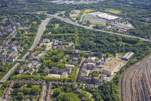 Aerial view, Hamborn municipal park, on the right Helios St. Johannes Klinikum Duisburg at the marshalling yard and abbey cemetery with St. Johann, abbey grammar school and abbey primary school, Gottfried-Wilhelm-Leibniz comprehensive school public school, above motorway junction Duisburg-Nord and Ikea furniture store, Alt-Hamborn, Duisburg, Ruhr area, North Rhine-Westphalia, Germany, railway area, burial ground, education, educational institution, DE, Europe, cemetery, memorial site, comprehensive school, railway tracks, tracks, Gottesacker, large construction site, primary school, graves, burial ground, grammar school, educational institute, aerial view, aerial photography, aerial photography, resting place, school, overview, bird's-eye view, forest, birds-eyes view, overview