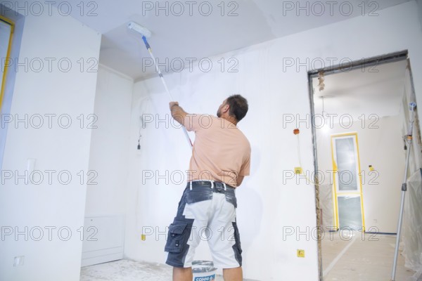 Wallpapering work: Priming the ceiling for the application of wallpaper