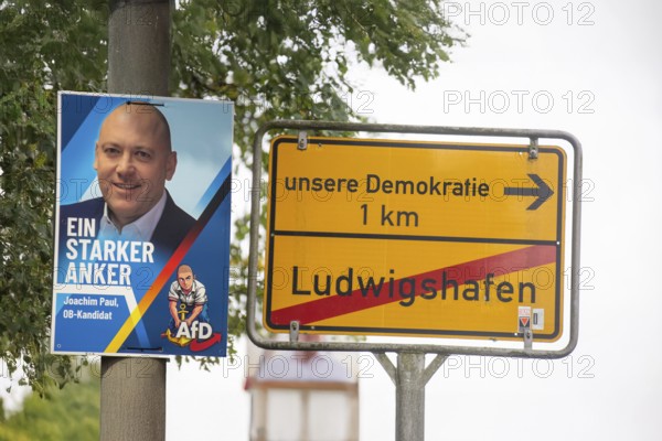 (Photomontage) Poster of the expelled Ludwigshafen mayoral candidate Joachim Paul (AfD), next to a town exit sign with the text LUDWIGSHAFEN / UNSERE DEMOKRATIE