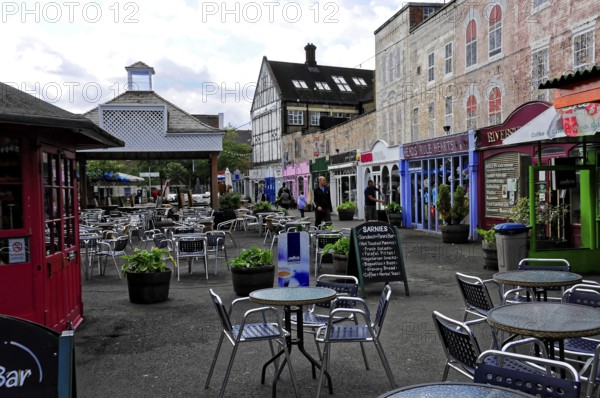 Colourful shops and empty tables at a busy market under a cloudy sky, London, England, United Kingdom