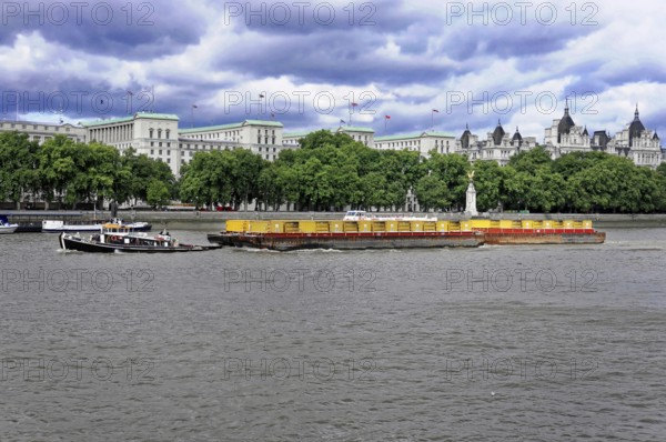 A barge on the Thames with historic buildings in the background on a cloudy day, London, England, United Kingdom