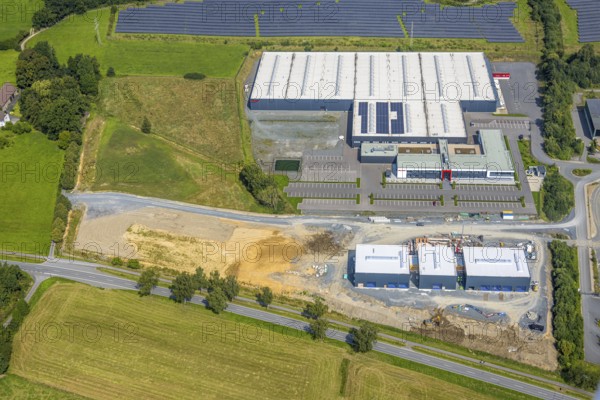 Aerial view, industrial area Enste-Süd with solar park Enste at the motorway A46, construction site with new building logistics centre Briloner Leuchten GmbH, Enste, Meschede, Sauerland, North Rhine-Westphalia, Germany, motorway A46, construction work, construction area, construction site, building plots, construction project, construction site, DE, Europe, commercial enterprises, commercial area, commercial area, commercial park, commercial site, commercial use, large construction site, industrial area, industrial building, industrial site, aerial view, aerial photography, aerial photography, new construction, photovoltaic, photovoltaic plant, Ruhr area, solar, solar plant, solar energy, solar park, overview, bird's-eye view, birds-eyes view, overview