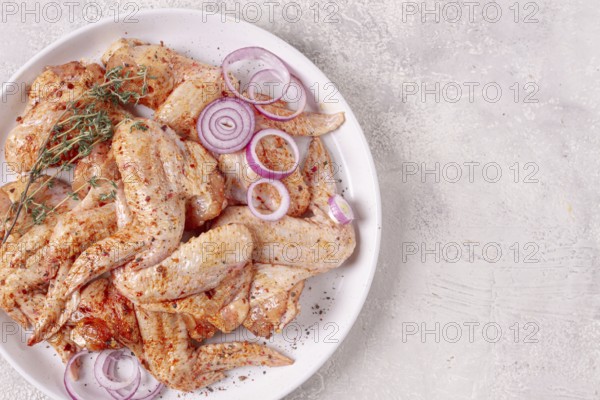Raw chicken wings, marinated with spices, on a white plate, no people