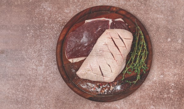 Fresh raw duck breasts, on a wooden chopping board, with herbs and spices, no people