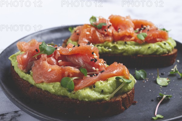 Breakfast, Sandwiches with smoked salmon and avocado, on dark rye bread, with microgreens, on a marble table, homemade, no people