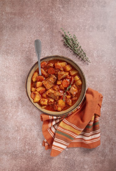 Meat goulash with potatoes and carrots, sweet peppers, in a saucepan, top view, traditional Hungarian soup, homemade, no people
