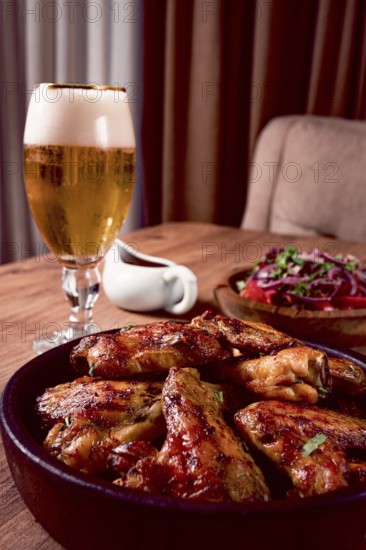 Delicious barbecue chicken wings, with French fries, salad and a refreshing drink, at a cozy table, there are no people