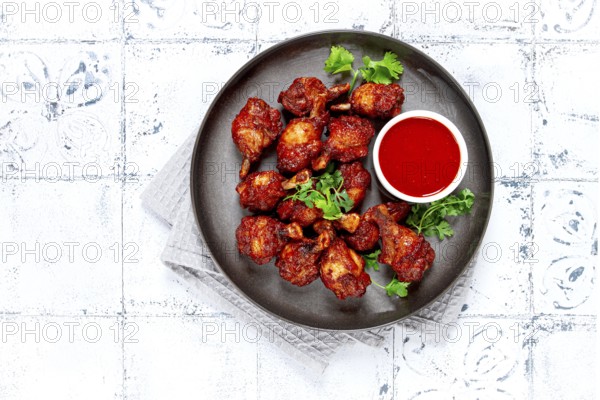 Crispy pieces of fried chicken, on a plate with sauce and herbs, in a modern kitchen environment, there are no people