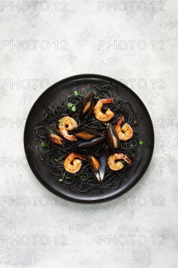 Black spaghetti with shrimp and mussels, on a black plate, spaghetti with shrimp, spaghetti with mussels, top view, no people