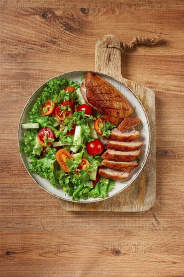 Delicious grilled duck breast served with fresh garden salad and cherry tomatoes at a rustic dining table