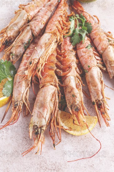 Shrimps on skewers, Grilled, spread on a marble surface, garnished, with lemon slices, and fresh herbs, view from above