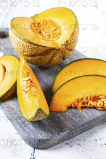 Freshly sliced melon slices, cantaloupe melon, on a wooden chopping board, close-up