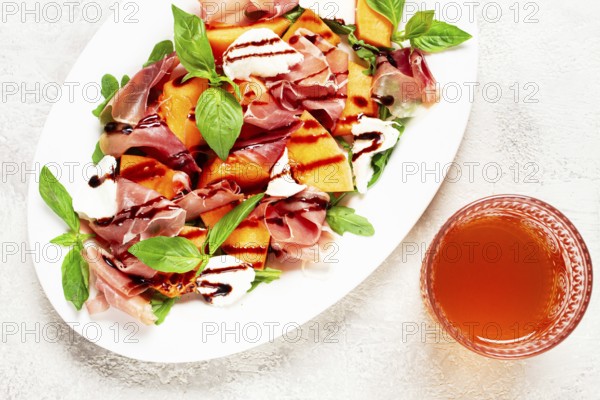 Salad with prosciutto and melon, with arugula and cheese, with balsamic sauce, natural light
