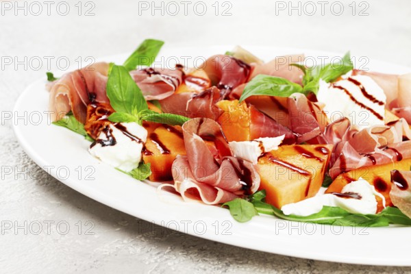 Salad with prosciutto and melon, with arugula and cheese, with balsamic sauce, natural light