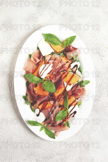 Salad with prosciutto and melon, with arugula and cheese, with balsamic sauce, natural light
