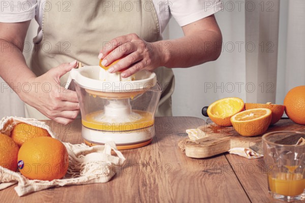Preparation of freshly squeezed orange juice, using a juicer, in a cozy kitchen setting