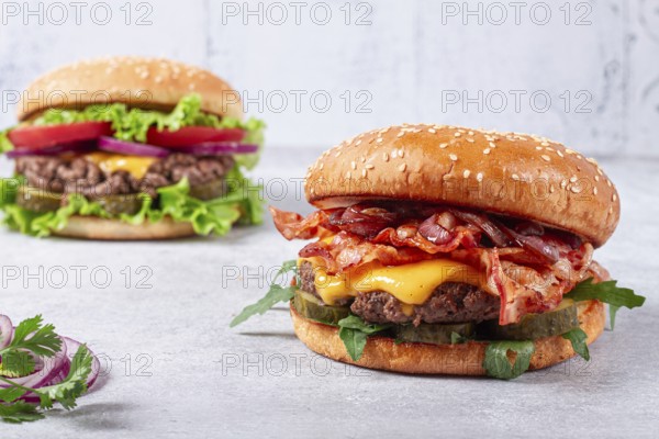 Two burgers with beef patty, fried bacon, cheddar cheese, tomatoes, homemade, no people