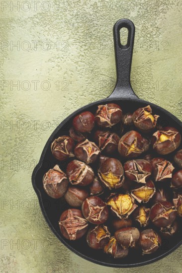 Roasted chestnuts, in an iron pan, wooden table, top view, no people, rustic style