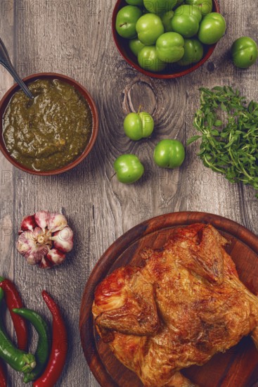 Baked tobacco chicken, served with tkemali sauce, on a wooden table, Georgian cuisine, rustic style, no people