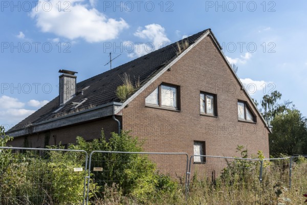 Overgrown house behind fence with plants on the roof, Manheim, North Rhine-Westphalia, Germany
