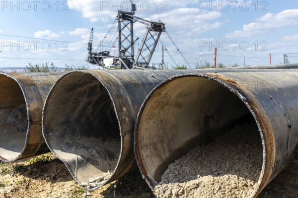 Large excavator in open-cast mine with pipes in the foreground, Manheim, North Rhine-Westphalia, Germany