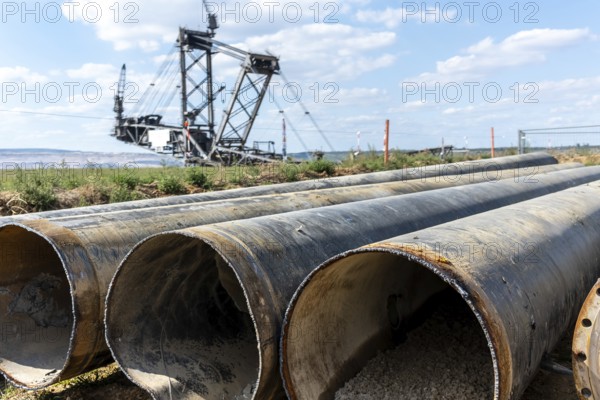 Large excavator in open-cast mine with pipes in the foreground, Manheim, North Rhine-Westphalia, Germany
