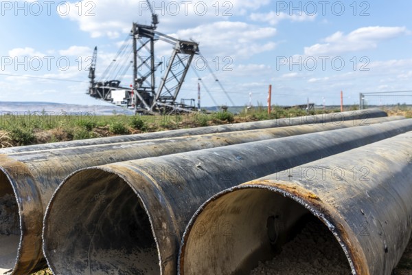 Large excavator in open-cast mine with pipes in the foreground, Manheim, North Rhine-Westphalia, Germany